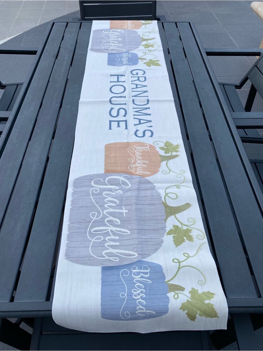 This is a festive fall table runner featuring blue watercolor-style pumpkins